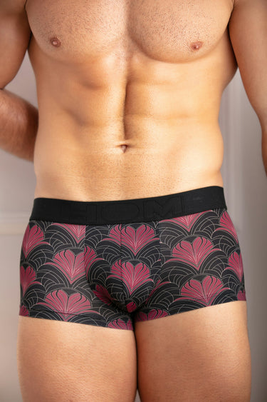Man wearing a black and red patterned underwear against a neutral background